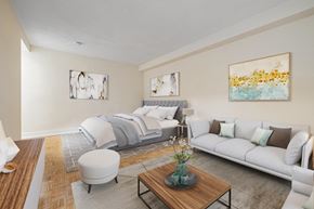 North York apartment for rent - A modern living room with a white couch, a wooden coffee table, and two framed artworks on the wall.