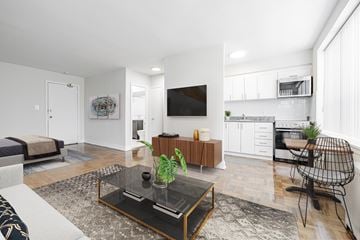 Toronto apartment for rent - A modern living room with a glass coffee table and a TV on the wall.