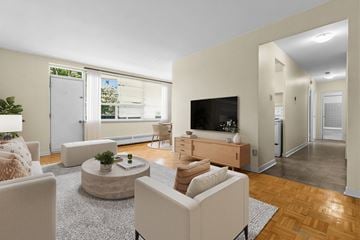 Etobicoke apartment for rent - A living room with a white sofa, a coffee table, a television, and a plant.