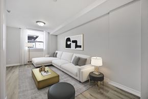 North York apartment for rent - A modern living room with a white sofa, a gold side table, and a grey ottoman.