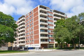 North York apartment for rent - A large red brick apartment building with trees in front.