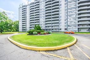 North York apartment for rent - A roundabout with a grassy island in the middle and a building in the background.