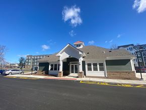 Milford apartment for rent - A building with a white front and a red roof is in front of a blue sky.