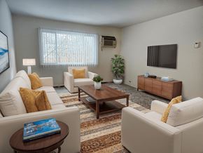 Armada apartment for rent - A living room with a white couch, a brown coffee table, and a flat screen TV mounted on the wall.