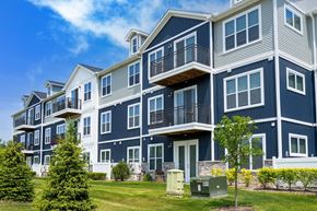 Walled Lake apartment for rent - a row of blue apartment buildings with balconies and trees