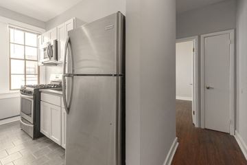Detroit apartment for rent - A kitchen with a stainless steel refrigerator and a microwave above the stove.