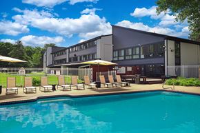 Waterford Township apartment for rent - A swimming pool in front of a building with sun loungers.