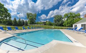 Bloomfield Hills apartment for rent - A large swimming pool surrounded by blue lounge chairs and trees.