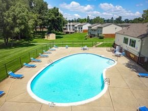 Waterford apartment for rent - A large swimming pool surrounded by a fence and trees.