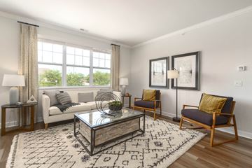 Novi apartment for rent - A living room with a white couch, a glass coffee table, and a rug with letters on it.