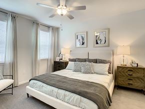 Orlando apartment for rent - A bedroom with a large bed, a ceiling fan, and two nightstands.