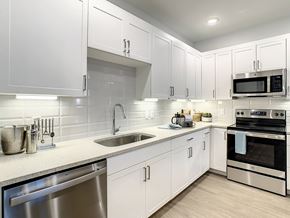 Orlando apartment for rent - A modern kitchen with white cabinets and stainless steel appliances.