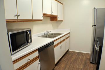 Saginaw apartment for rent - A kitchen with white cabinets and a black fridge.