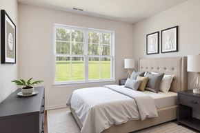 Howell apartment for rent - A bedroom with a large bed and a window overlooking a green lawn.