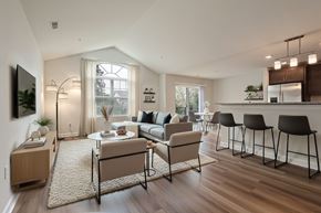Brighton apartment for rent - A modern living room with a large window, a dining table set for two, and a kitchen area in the background.
