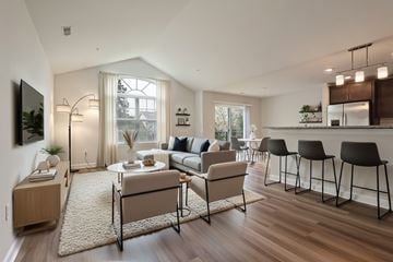 Brighton apartment for rent - A modern living room with a large window, a dining table set for two, and a kitchen area in the background.