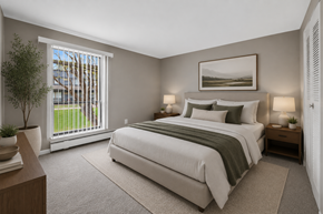 Waterford Township apartment for rent - A bedroom with a large bed and a view of the outside through the window.