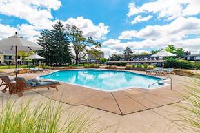 Southfield apartment for rent - A large outdoor swimming pool surrounded by a concrete patio and deck chairs.