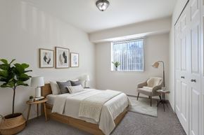 Waterford apartment for rent - A bedroom with a bed, chair, and a plant.