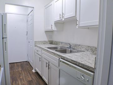 Livonia apartment for rent - A kitchen with white cabinets and a marble countertop.