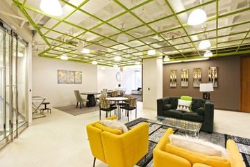 St. Louis townhouse for rent - A living room with a yellow chair and a glass coffee table.