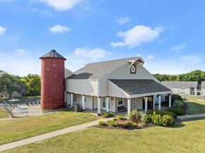 Peoria apartment for rent - A red brick tower stands next to a white building with a gabled roof.
