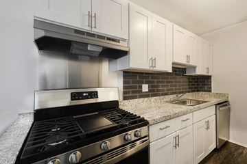 Madison Heights apartment for rent - A modern kitchen with a black stove top oven and white cabinets.