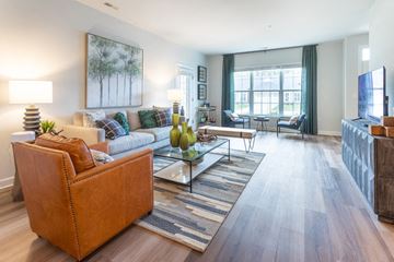 Commerce Township apartment for rent - A living room with a brown leather couch and a glass coffee table.