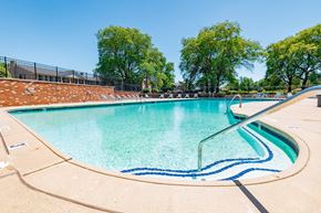 Grand Blanc apartment for rent - A large outdoor swimming pool with a blue line in the middle.