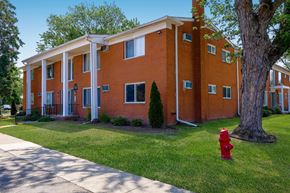 Livonia apartment for rent - A red fire hydrant sits on a green lawn in front of a red brick building.