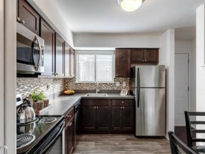 West Bloomfield apartment for rent - A kitchen with dark wood cabinets and a stainless steel refrigerator.
