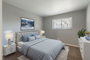 Trenton apartment for rent - A bedroom with a large bed, a nightstand with a lamp, and a painting on the wall.