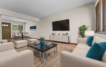 Peoria apartment for rent - A living room with a white couch, a glass coffee table, and a flat-screen TV mounted on the wall.