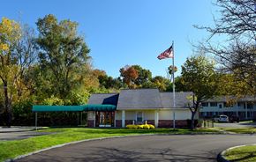 Waterford apartment for rent - A building with a flag on top is surrounded by trees.