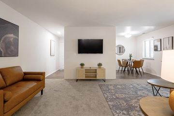Auburn Hills apartment for rent - A living room with a brown couch and a flat screen TV mounted on the wall.