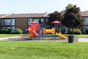 Warren apartment for rent - A playground with a red slide and yellow slide in front of a building.