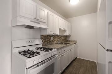 Madison Heights apartment for rent - A kitchen with white cabinets and a white stove top oven.