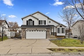 Layton apartment for rent - A two-story house with a garage is surrounded by a driveway and a sidewalk.