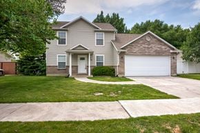 Lehi apartment for rent - a beige house with a white garage door and a lawn