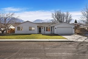 Provo apartment for rent - the front of a white house with a yard and mountains in the background