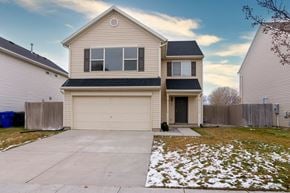 Saratoga Springs apartment for rent - a beige house with a garage door and a snowy yard