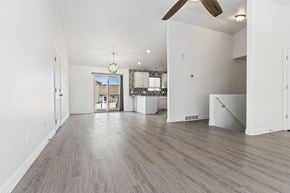 West Jordan apartment for rent - A spacious room with a ceiling fan and lighting fixture.