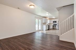 Lehi apartment for rent - the living room and kitchen of a new home with white walls and wood floors