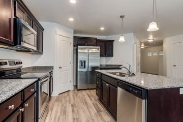 Saratoga Springs apartment for rent - A modern kitchen with dark wood cabinets and stainless steel appliances.