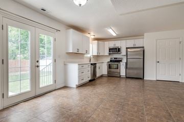 Lehi apartment for rent - A kitchen with white cabinets and brown tile flooring.