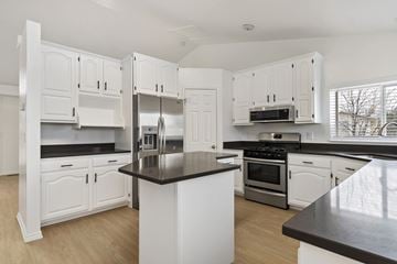 Kaysville apartment for rent - A kitchen with white cabinets and a black countertop.