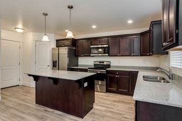 Saratoga Springs apartment for rent - A kitchen with dark brown cabinets and a white countertop.