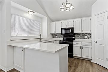 Layton apartment for rent - A kitchen with white cabinets and a black stove top oven.