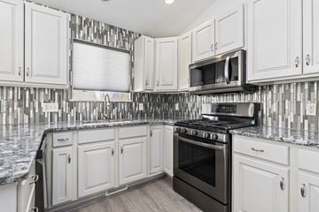 West Jordan apartment for rent - A kitchen with white cabinets and a black stove top oven.