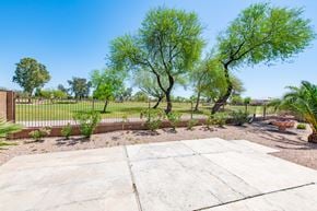 Queen Creek apartment for rent - the backyard has a fence with trees and a grassy field in the background